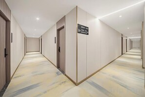 A hotel corridor with doors, a carpeted floor, and a sign indicating the direction to the 2nd floor. - Jiangmen ParkLane Hotel (Xiangshan Park Xinqiao Branch) (Jiangmen)