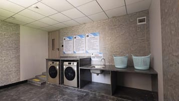 A laundry area with washing machines, a sink, and laundry baskets.