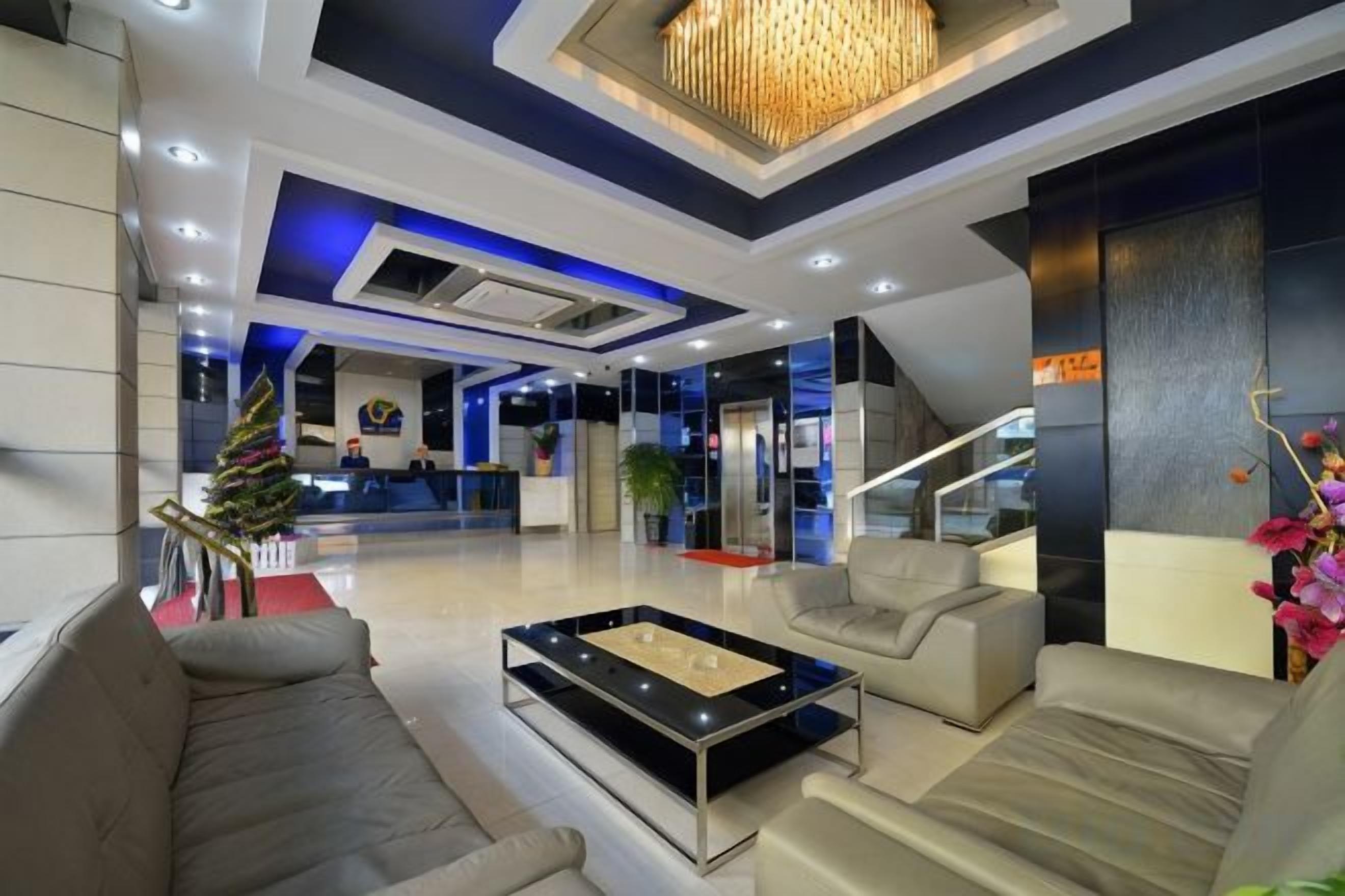 A modern lobby with a reception desk, seating area, and a staircase.