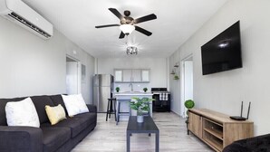 A modern living room with a sofa, a coffee table, a TV, and a ceiling fan. - VelBELA Rincon (Rincon)