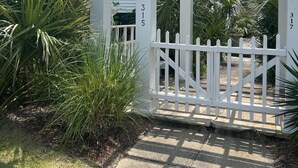 A white pergola with a white picket fence in front of a building with the number 315 visible.