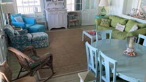 A spacious living room with a large window, a dining area with a table and chairs, and a cozy seating area with a sofa and chairs.