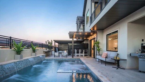 Un espace piscine extérieur moderne, doté d’un jacuzzi, de chaises longues et d’une terrasse avec mobilier d’extérieur.