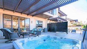 Un área moderna con jacuzzi al aire libre, asientos y una pérgola.