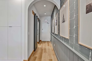 Stylish hallway with a herringbone floor, framed artwork, and a decorative tree element.