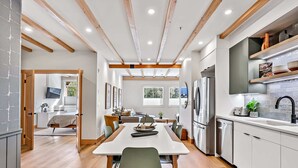 A modern kitchen with wooden beams, white cabinets, and stainless steel appliances. - Raven's Nest - Perfectly Located on Main Street (Canmore)