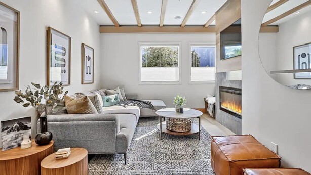 A modern living room with a fireplace, a sofa, a coffee table, and a rug. - Raven's Nest - Perfectly Located on Main Street (Canmore)