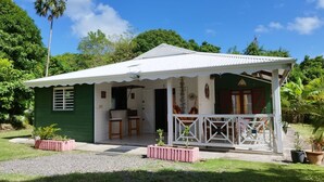 A small, single-story house with a porch, a small kitchen area, and a green exterior. - LES FLAMBOYANTS LA PETITE MAISON CRÉOLE (Anse-Bertrand)