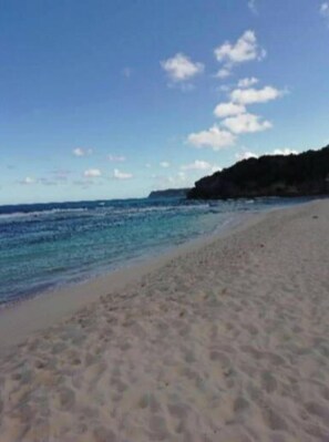 Een strand met helderblauw water en een zandstrand.
