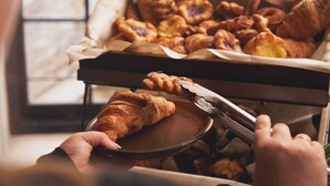 A tray of assorted pastries, including croissants and tarts, being served.