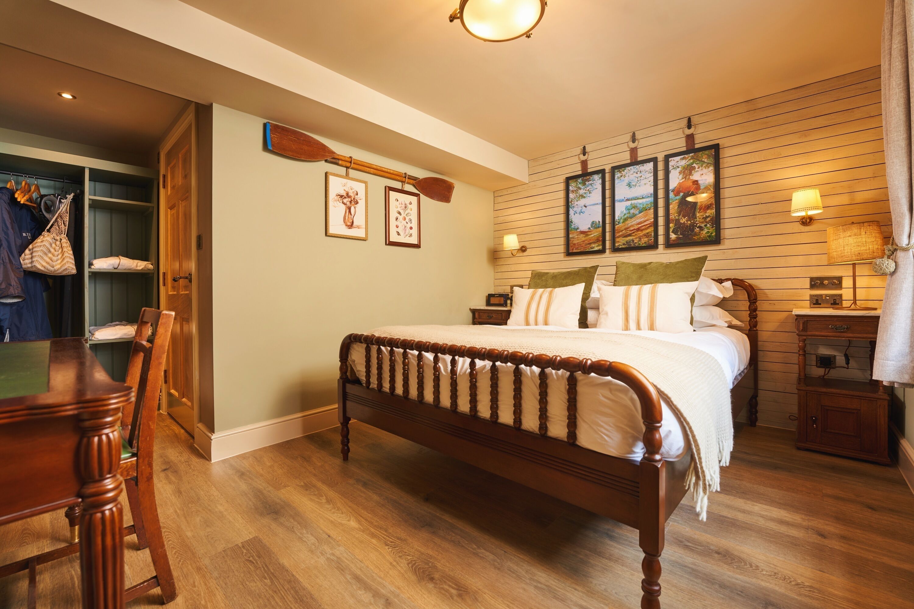 A bedroom with a wooden bed, a wooden dresser, a nightstand, and a wall-mounted lamp.