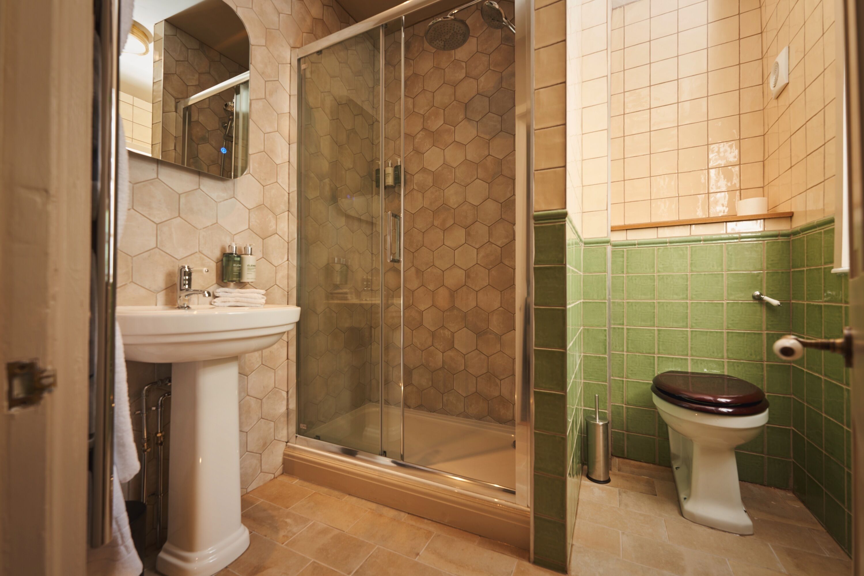 A bathroom with a glass-enclosed shower, a pedestal sink, and a toilet.
