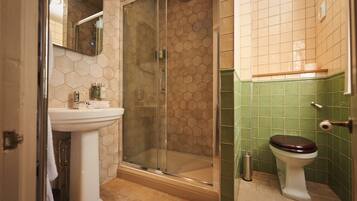 A bathroom with a glass-enclosed shower, a pedestal sink, and a toilet.