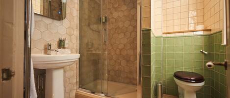 A bathroom with a glass-enclosed shower, a pedestal sink, and a toilet.