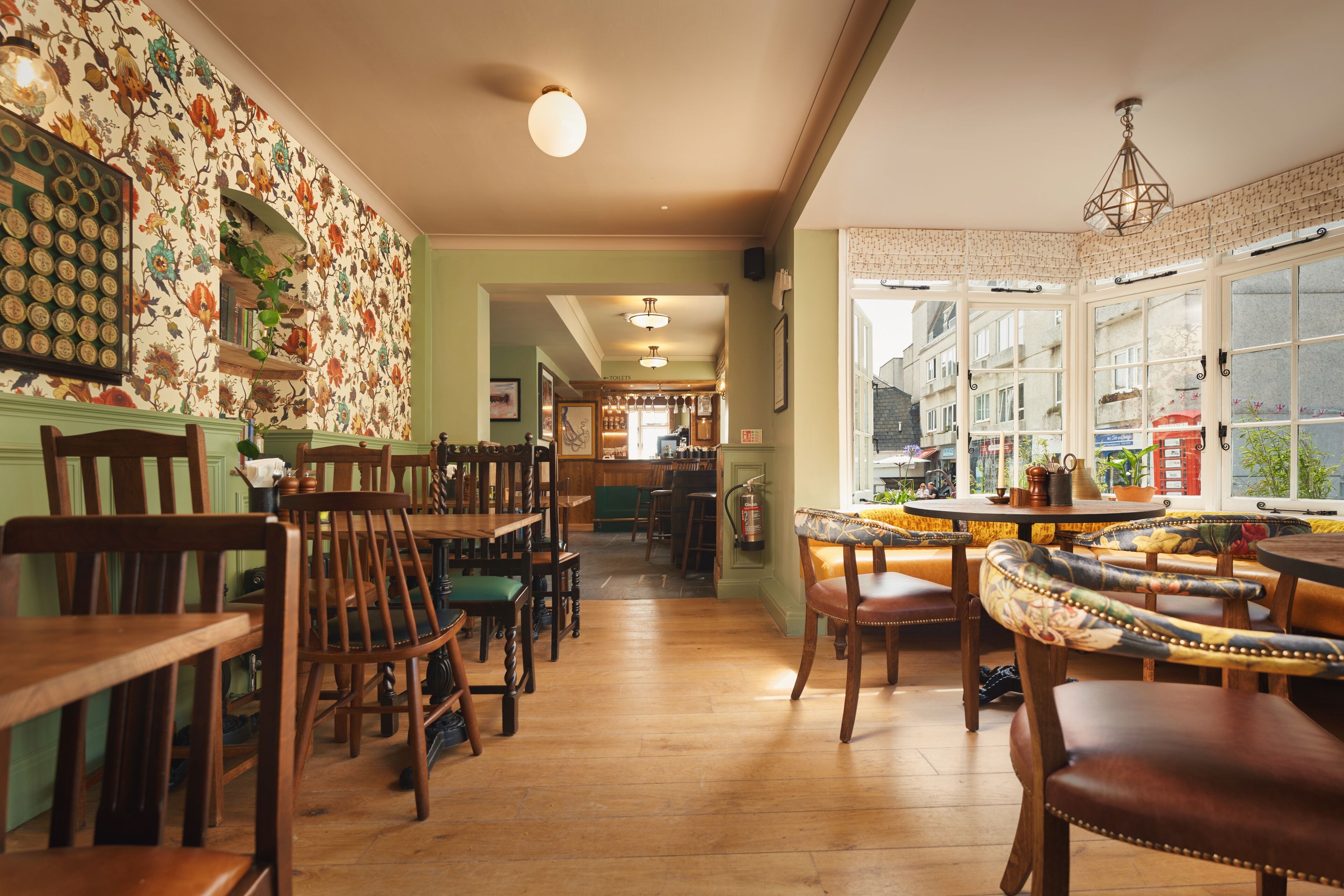 Un restaurante acogedor con muebles de madera, un muro con diseño y vistas amplias a través de grandes ventanales.