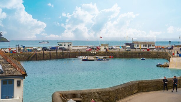 A harbor with boats, a stone wall, and a building with a blue door.