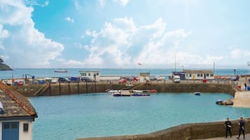 Un puerto con barcos, un muro de piedra y un edificio con puerta azul.