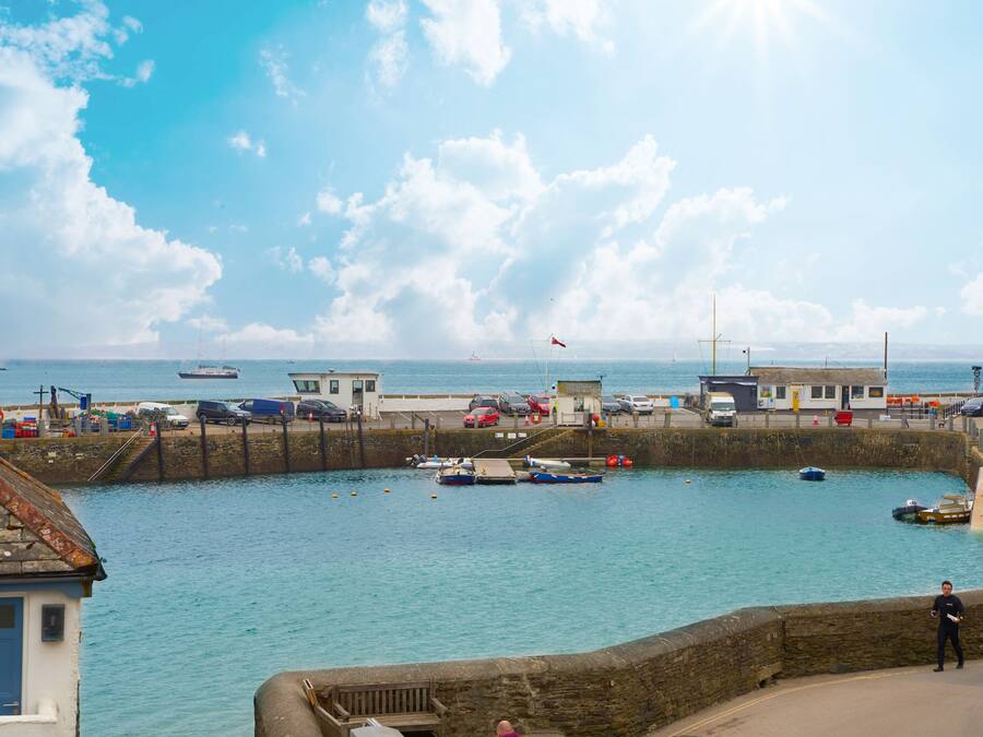 A harbor with boats, a stone wall, and a building with a blue door.