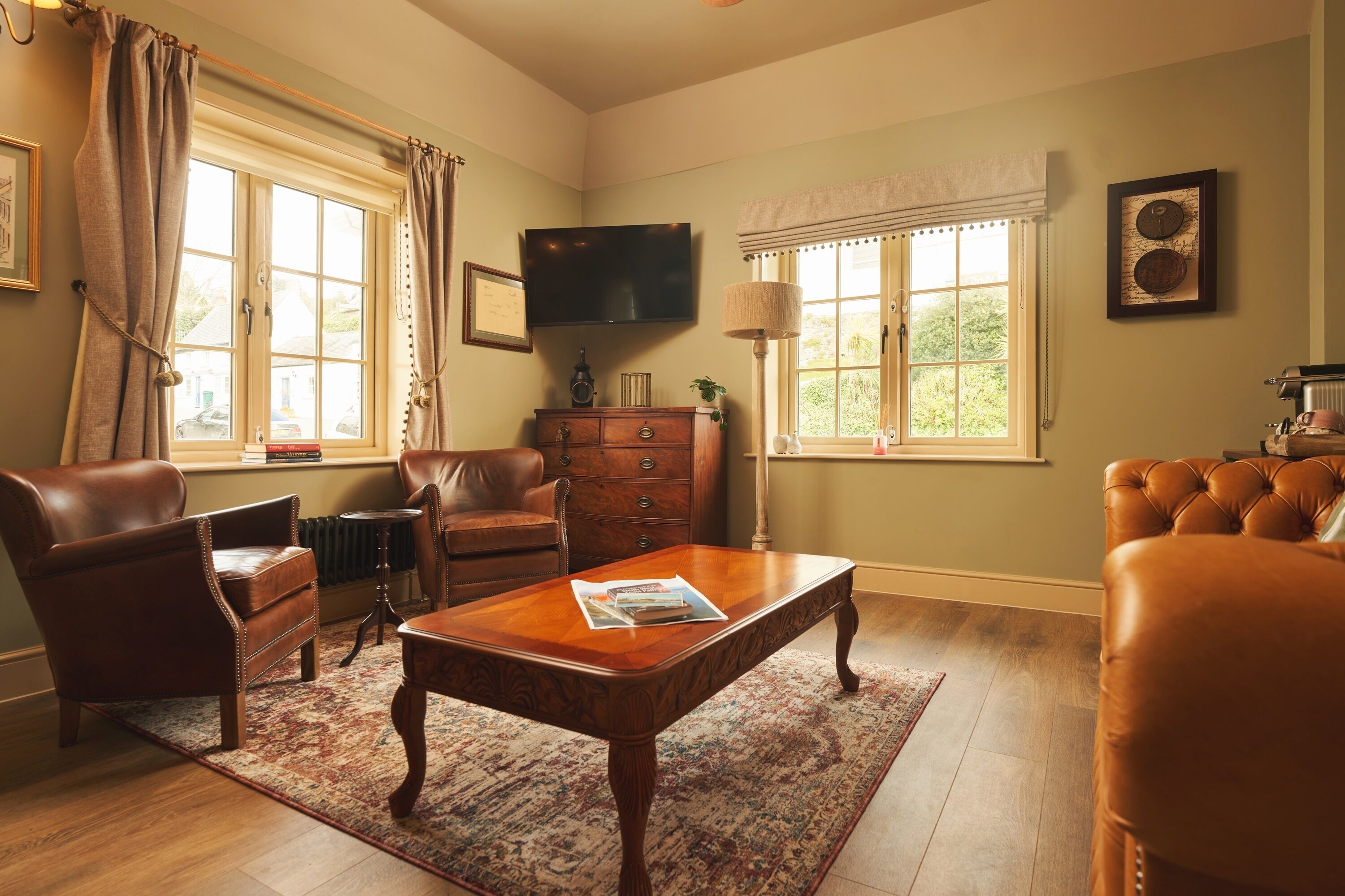 A spacious living room with a leather sofa, a wooden coffee table, and a television on the wall.