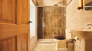 A bathroom with a wooden door, a toilet, a sink, and a shower area.
