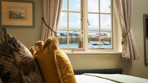 A bedroom with a large window overlooking a marina, a framed picture on the wall, and a radiator under the window.