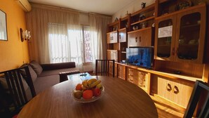 A living room with a wooden dining table, a television, and a cabinet with glass doors. - Plaza Universitat Apartment (Barcelona)