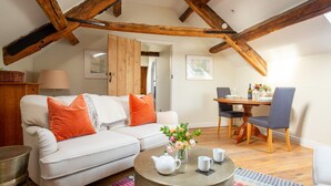 A cozy living room with a sofa, a dining table with chairs, and a coffee table with a teapot and cups.