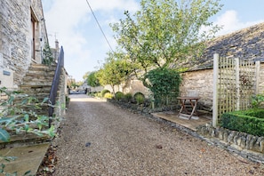 A gravel path leading to a stone gate, surrounded by stone walls and greenery.