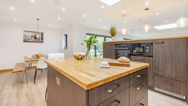 A modern kitchen with a wooden island, built-in appliances, and pendant lighting. - Three bedroom dog friendly holiday home in the Cotswolds - The New Bakehouse (Stroud)