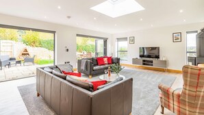 A spacious living room with a large sectional sofa, a flat-screen TV, and a fireplace. - Three bedroom dog friendly holiday home in the Cotswolds - The New Bakehouse (Stroud)