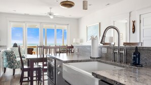 Una cocina con una isla grande, un comedor con vistas y un ventilador de techo.
