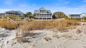 Una propiedad frente al mar con una casa amplia que cuenta con un porche envolvente y múltiples ventanas.