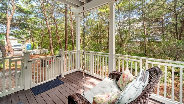 A covered porch with a swing chair and a view of a wooded area. - 0.2 miles from the beach In the heart of Seagrove (Santa Rosa Beach)
