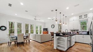 A modern kitchen with white cabinetry, a central island, and a dining area with a round table and chairs. - 0.2 miles from the beach In the heart of Seagrove (Santa Rosa Beach)
