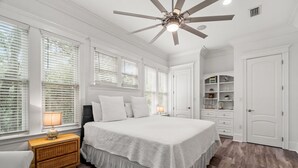 A bedroom with a large bed, white walls, a ceiling fan, and a built-in shelving unit. - 0.2 miles from the beach In the heart of Seagrove (Santa Rosa Beach)