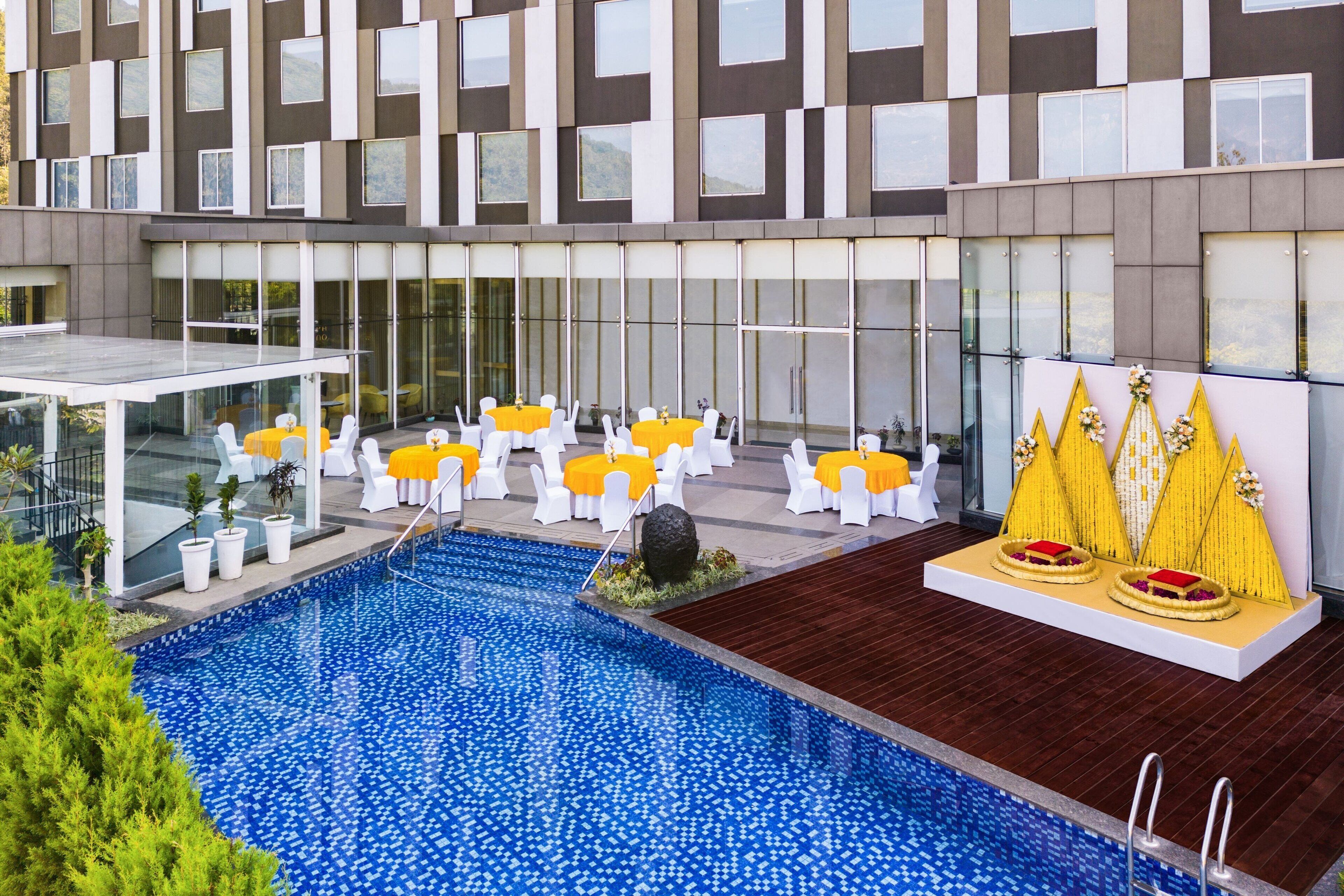 A modern hotel with a swimming pool, outdoor seating area, and a decorative wall.