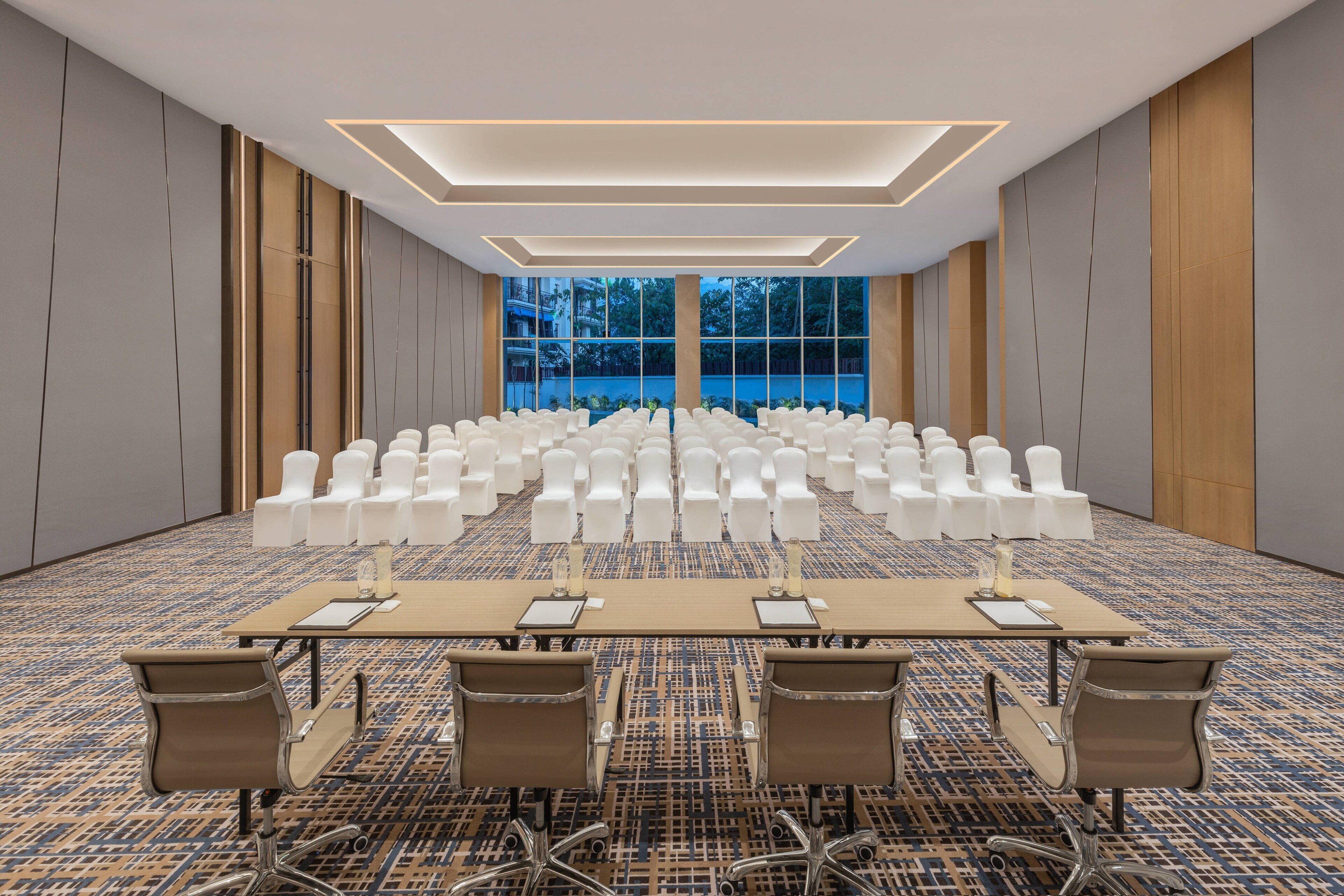 Un salón de conferencias con una mesa larga, varias sillas y suelo alfombrado.