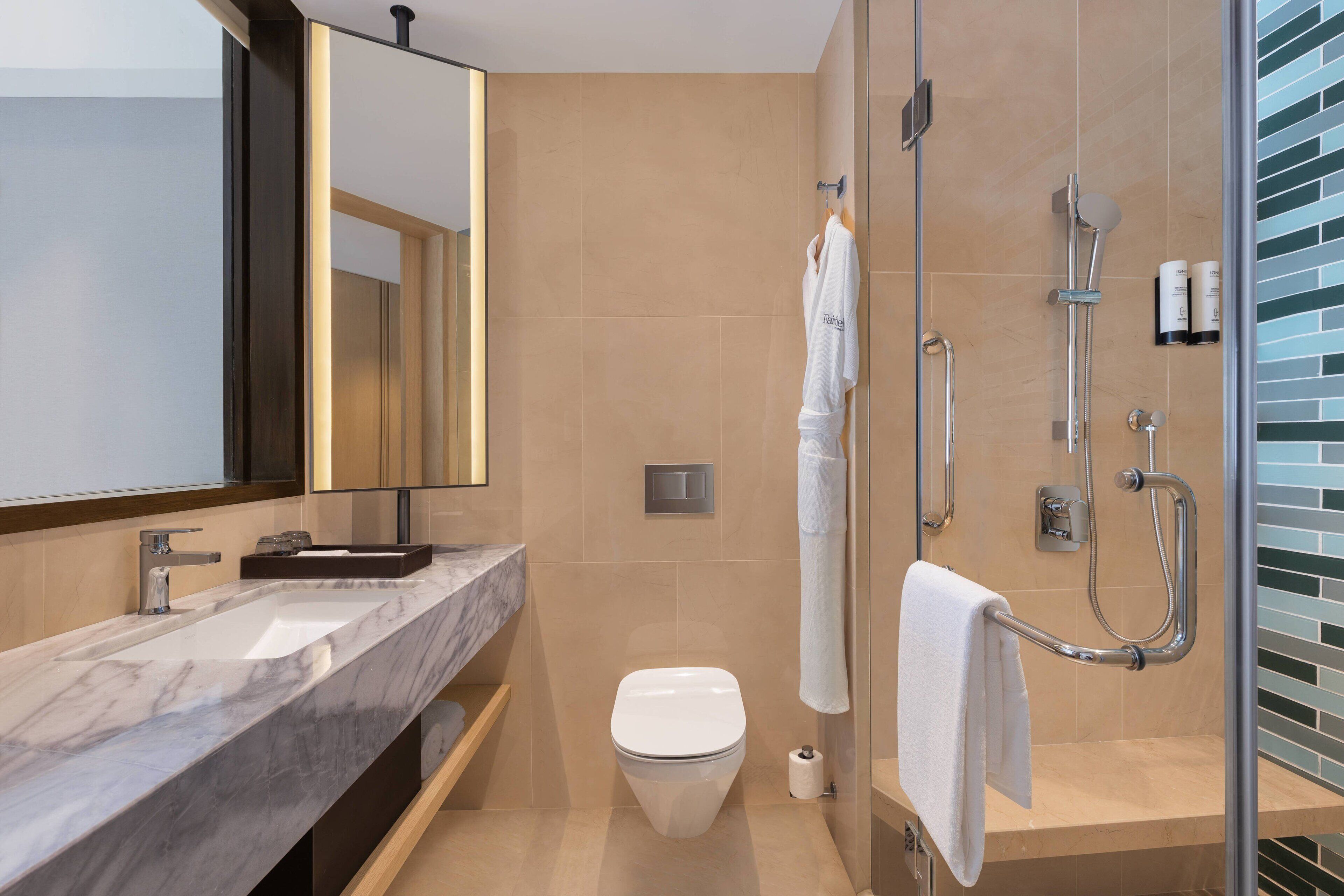 A modern bathroom with a marble sink, a toilet, a glass-enclosed shower, and a mirror with a dark frame.