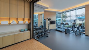 Un gimnasio moderno con equipamiento de ejercicio, una estación de agua y amplias ventanas con vistas al exterior.