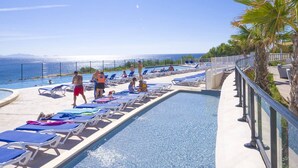 A poolside area with lounge chairs and a view of the sea. - Camping de l'Arquet Cote Bleue (Martigues)
