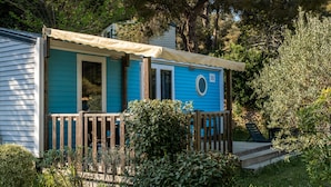 A blue mobile home with a wooden deck and a covered porch. - Camping de l'Arquet Cote Bleue (Martigues)