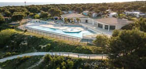 A residential area with a swimming pool, houses, and a lighthouse in the background.