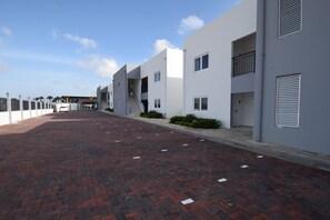 A modern building with a brick-paved driveway, white exterior walls, and a clear sky.