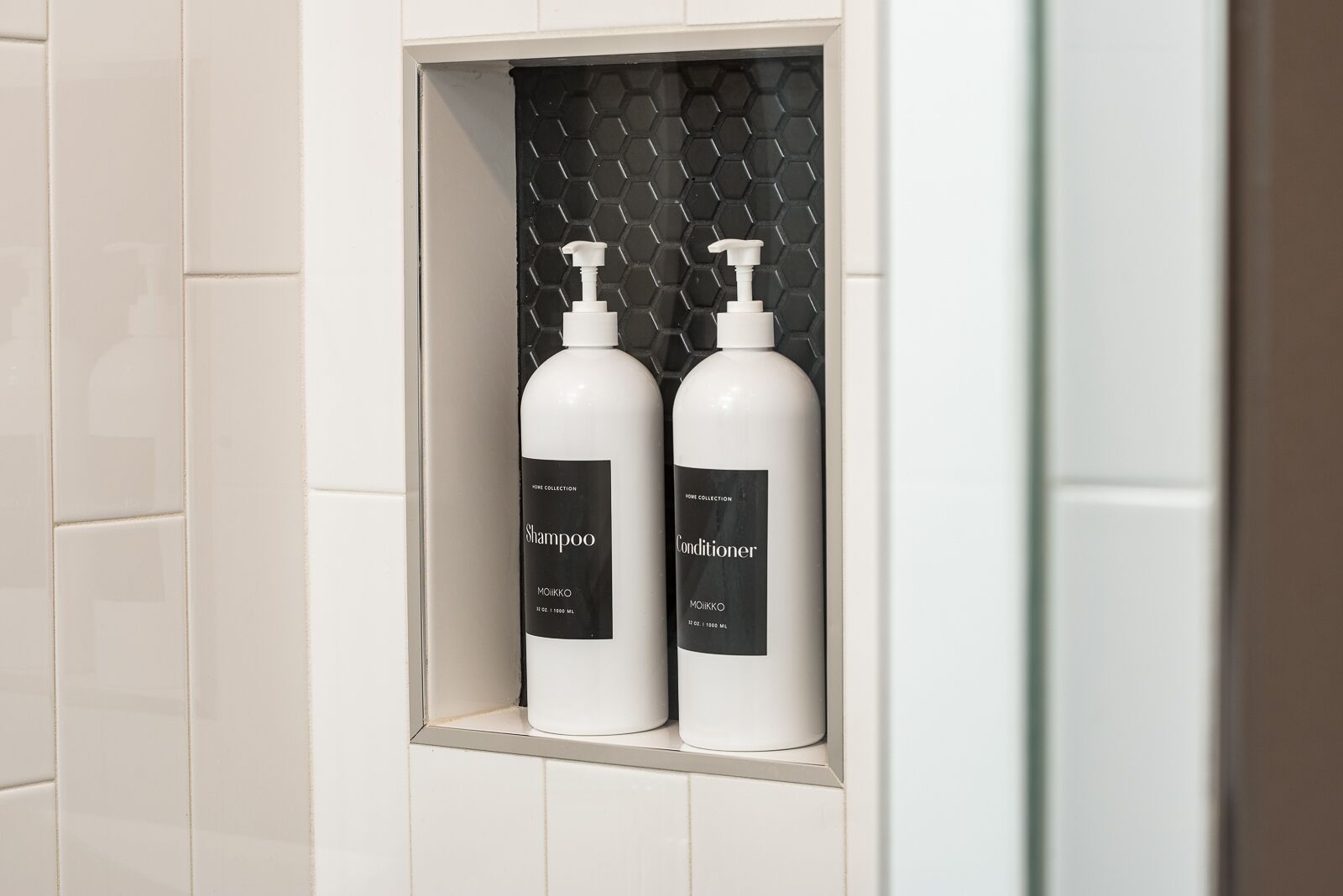 Two bottles of shampoo and conditioner in a bathroom shelf.