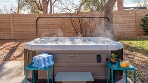 Ein Whirlpool mit Holzterrasse, einer Sitzbank und einem kleinen Tisch mit Handtüchern und Getränken.