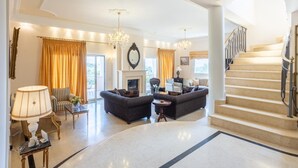 Un salón amplio con chimenea, dos sofás, una mesa de centro y una escalera que lleva a un piso superior.