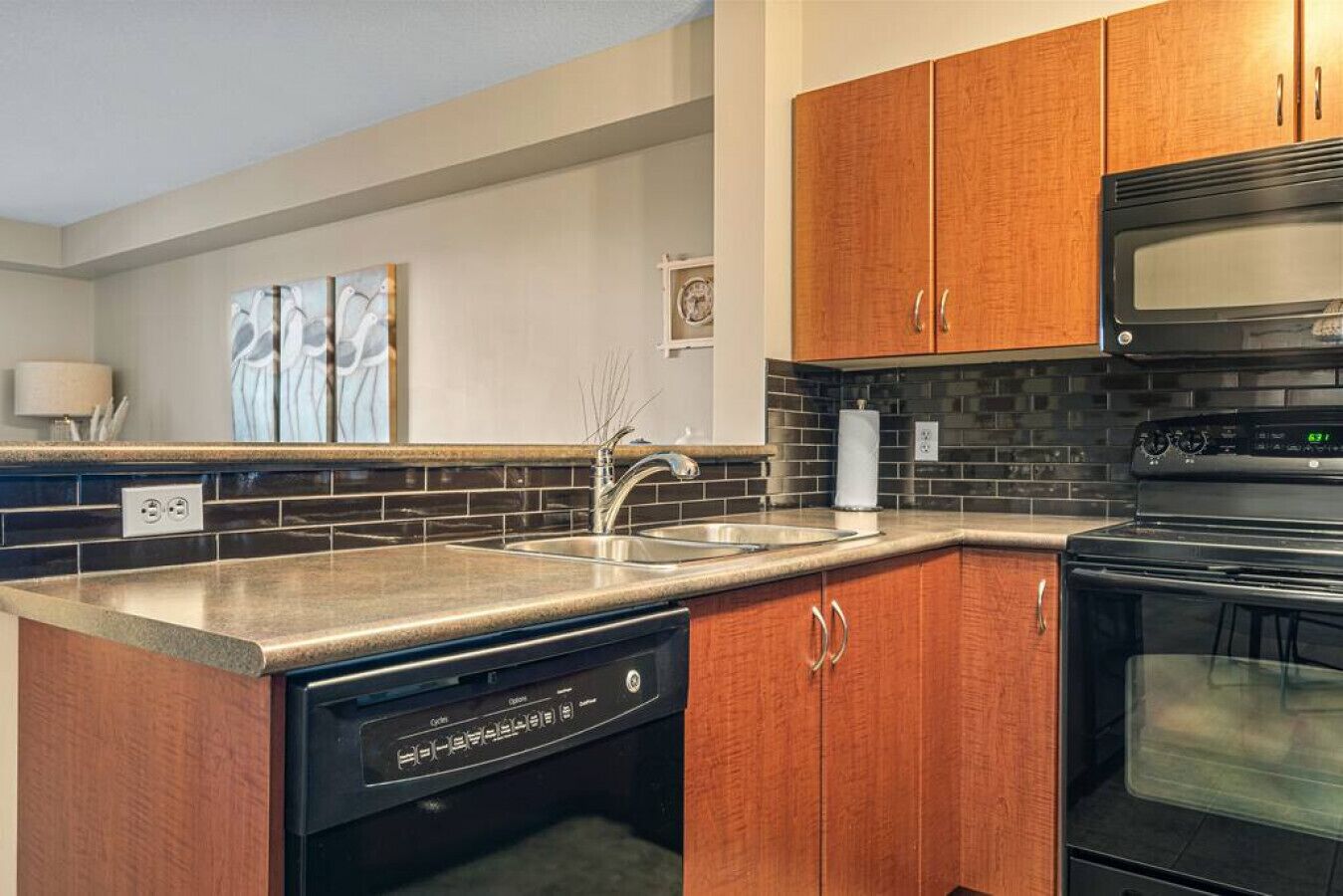 A modern kitchen with wooden cabinets, a stainless steel sink, and a built-in dishwasher.