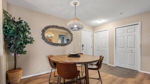 A dining area with a round wooden table, four chairs, a large mirror, and a hanging light fixture. - Modern Boho | Mountain Views | Pool | Hot Tub (Invermere)