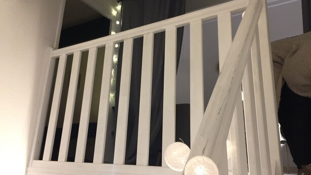 A white wooden staircase with a railing, a dark curtain, and two spherical light fixtures.