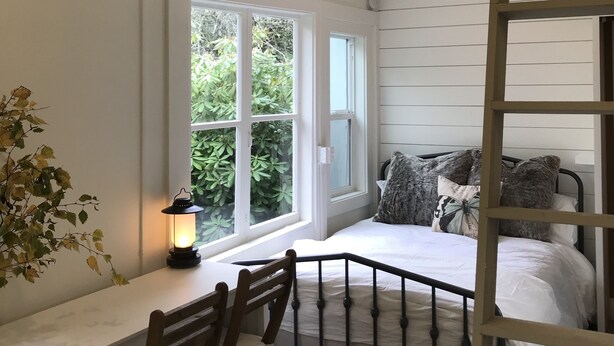 A room with a loft bed, a desk, and a chair. There is a window with a view of greenery outside. - Willow Studio near Vashon Town (Vashon)